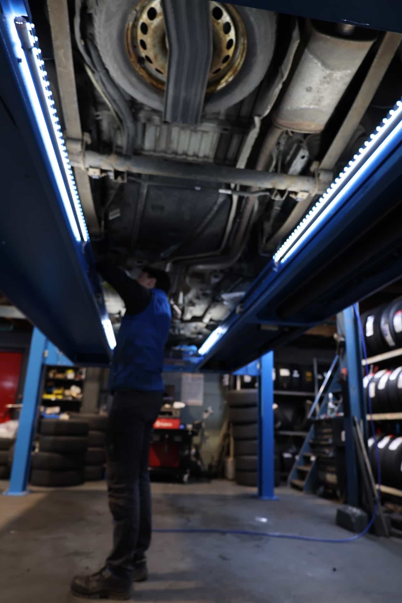 Monteur werkt aan de onderkant van een auto in de werkplaats in Volendam